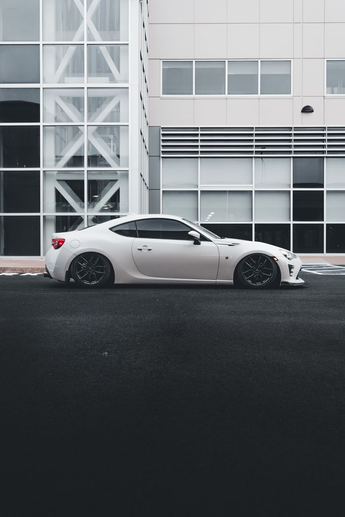 A stylish white sports car parked beside a contemporary office building.